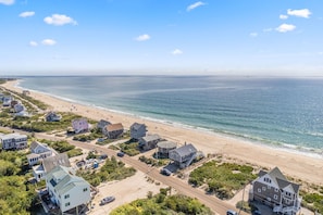 Luchtbeeld van een kustgebied met huizen, een strand en een weg.