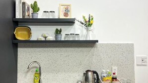 Una cocina moderna con un lavaplatos integrado, una cafetera y un estante con libros y plantas.