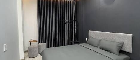 A modern bedroom with a bed, a small table, and a chair.
