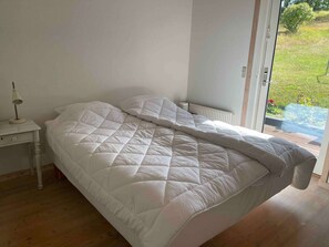 A bedroom with a bed, a bedside table, and a view of the outdoors. - 4 Star Holiday Home in Allinge (Allinge)