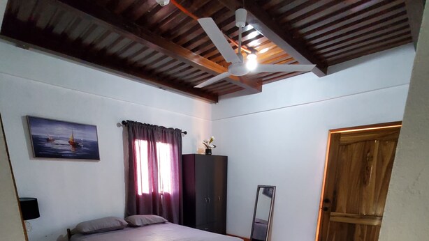 Un dormitorio con cama, armario, espejo y puerta.