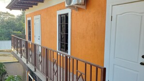 Un edificio con balcón, una puerta blanca y un equipo de aire acondicionado.