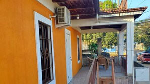 Un edificio con fachada naranja, una escalera de madera y un área de estar exterior cubierta.