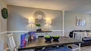 Un comedor con mesa de madera, sillas, un adorno en la pared y un sofá.