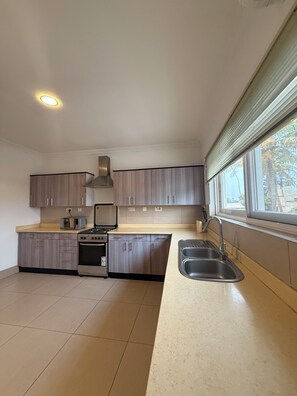 A kitchen with a stove, oven, microwave, and sink. - Secure Two Bedroom Apartment with Study (HR6M+HMV, Accra)
