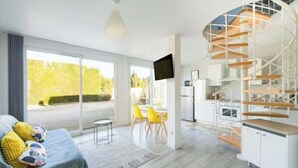 Un intérieur moderne avec un escalier en colimaçon, un coin repas et une grande fenêtre.