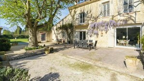 Un bâtiment en pierre doté d’une terrasse, de sièges extérieurs et d’un arbre.