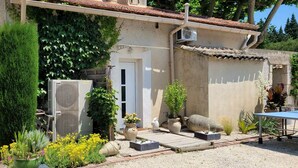 Une maison avec un jardin, un espace extérieur aménagé pour s’asseoir et un appareil de climatisation.