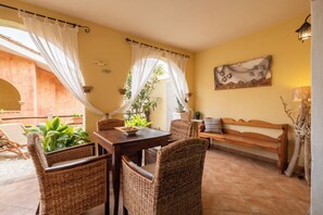 A dining area with wicker furniture, a wooden table, and a bench. - UR-SUN&SEA DOWNTOWN APARTMENT WITH VERANDA (Villasimius)