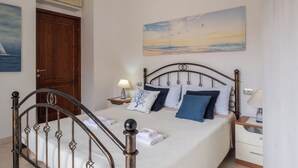 Ein Schlafzimmer mit einem Bett, einem Nachttisch, einer Lampe, einem Gemälde und einer Holztür.