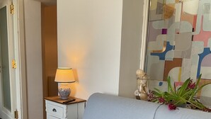 A light blue sofa in a room with a small table, a lamp, and a decorative glass piece. - Harmonies by the sea (Siracusa)