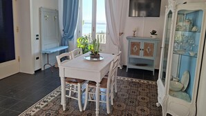 A dining area with a table, chairs, a blue cabinet, a mirror, and a view of the sea. - Harmonies by the sea (Siracusa)