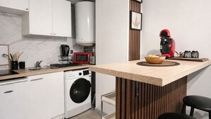 A modern kitchen with white cabinets, a built-in washing machine, a microwave, and a red coffee machine.