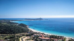 Una zona costera con una playa, un pueblo pequeño y una montaña al fondo.