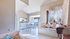 Una habitación con sofá, una mesa de comedor y vista al mar.