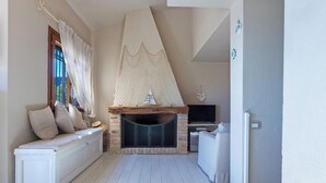 Una habitación acogedora con chimenea, televisión y zona de estar con cojines.