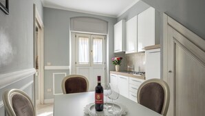 A dining area with a table, chairs, a wine bottle, and a glass. - Brunelleschi Elegant by MMega (Florence)