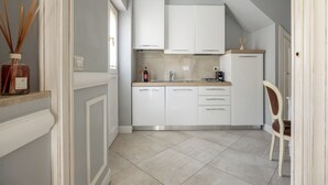 A kitchen with white cabinets, a countertop, a sink, and a chair. - Brunelleschi Elegant by MMega (Florence)