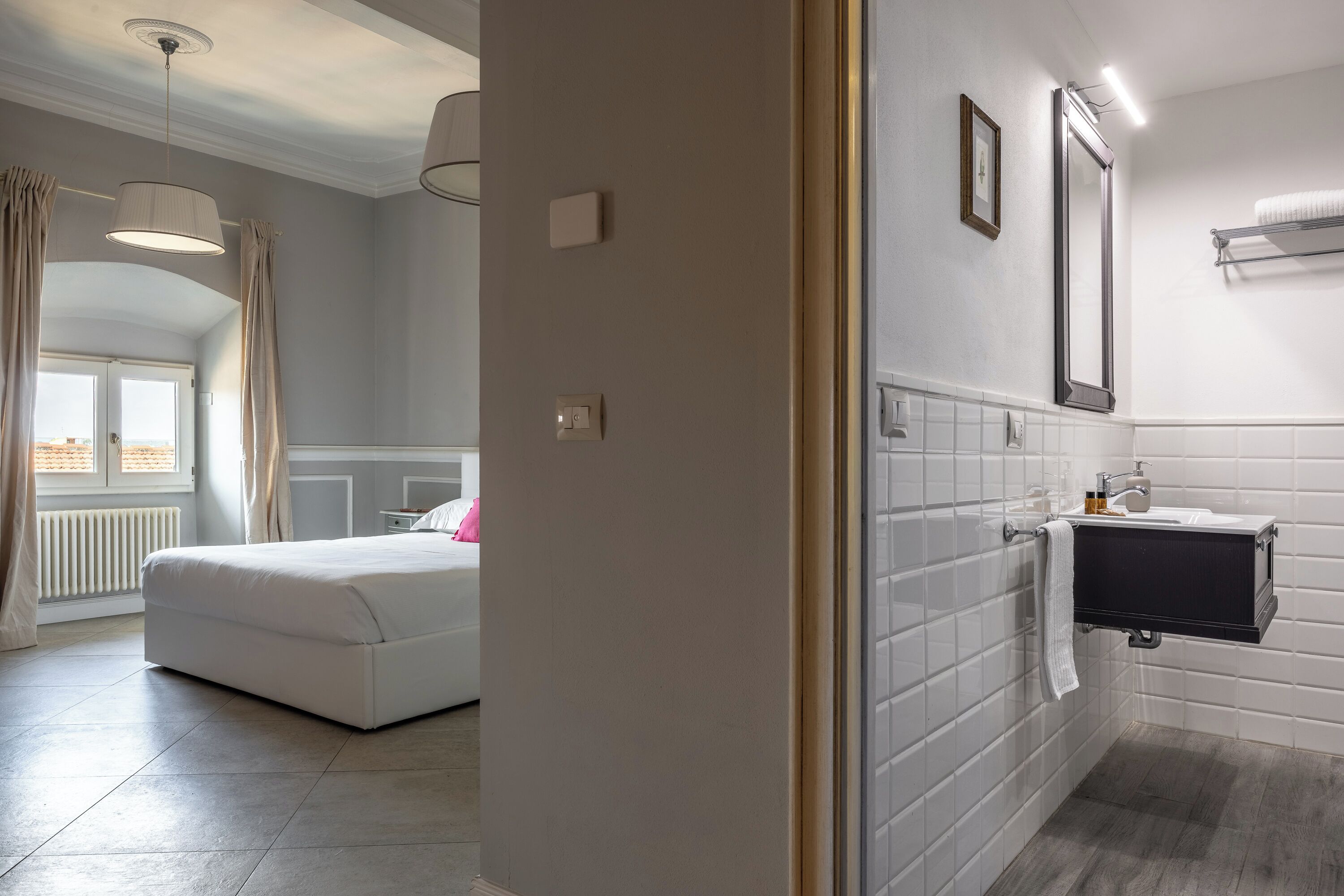 Une chambre d’hôtel avec un lit, une salle de bain avec un miroir et une fenêtre.