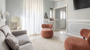 A living room with a grey sofa, a round pink chair, a lamp, and a TV mounted on the wall. - Brunelleschi Elegant by MMega (Florence)