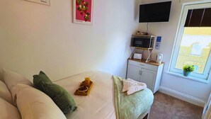 Et soveværelse med seng, puder, en bakke med morgenmad, et fladskærms-tv, en mikroovn og et vindue med udsigt.