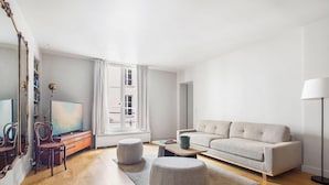Ein Wohnzimmer mit Sofa, Hocker, Couchtisch und Fernseher.
