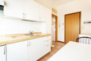 Eine moderne Küche mit weißen Schränken, einer Holz Arbeitsplatte und einem Spülbecken.