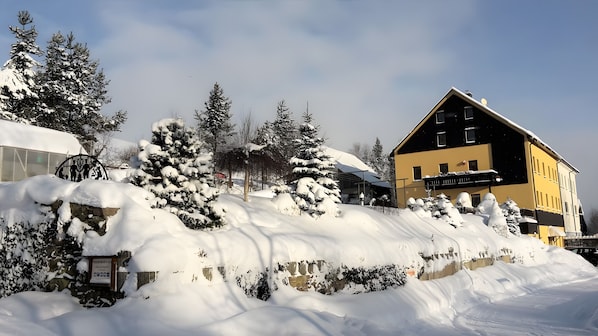 A snow-covered landscape with a building featuring a sign that reads 'Hotel.'