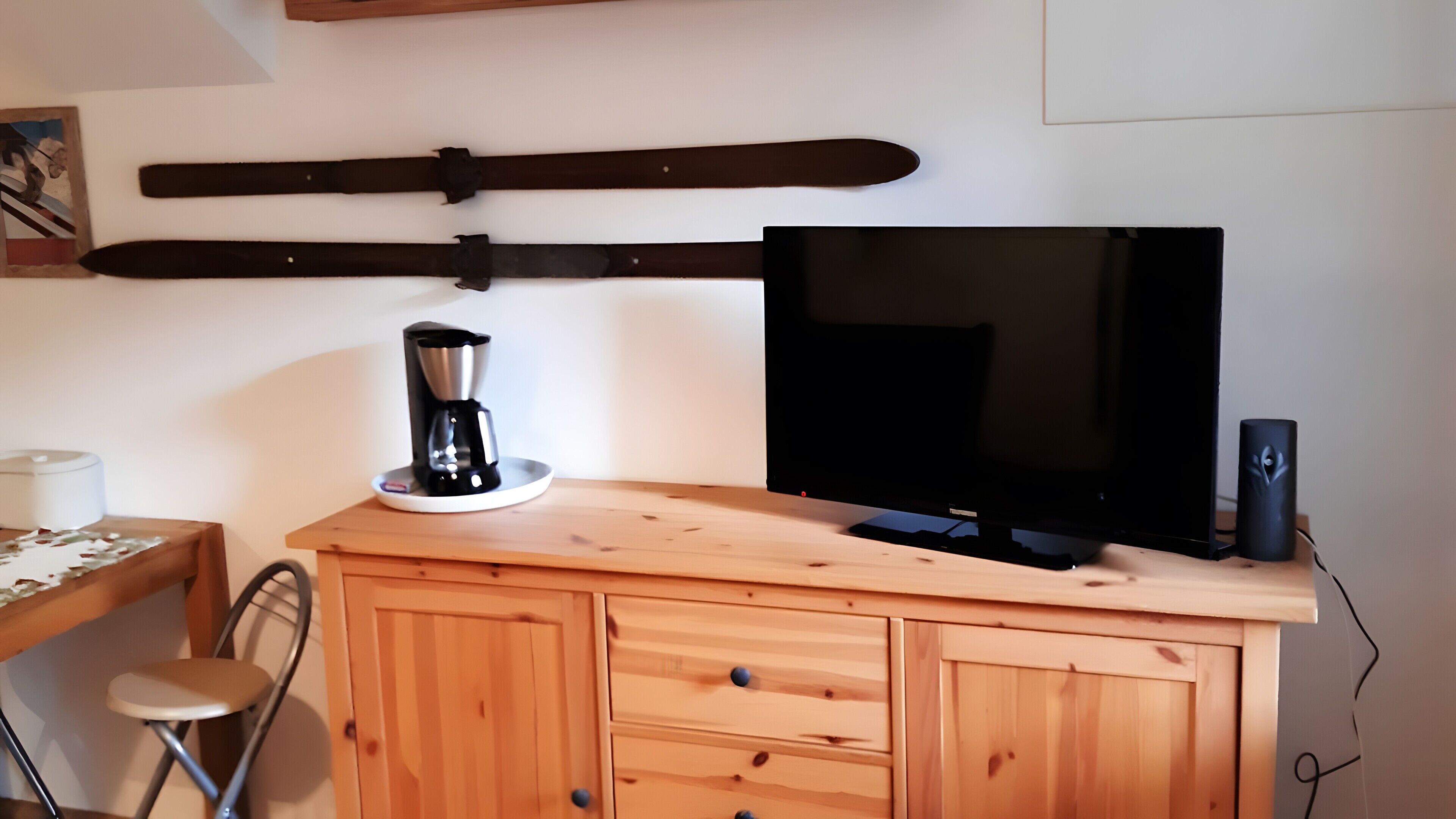 A wooden desk with a coffee maker, a television, and a speaker.