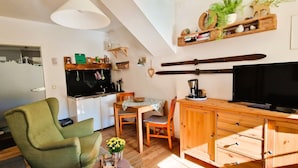 Eine gemütliche Küche mit Essbereich, Holzmöbeln und einem Fernseher.