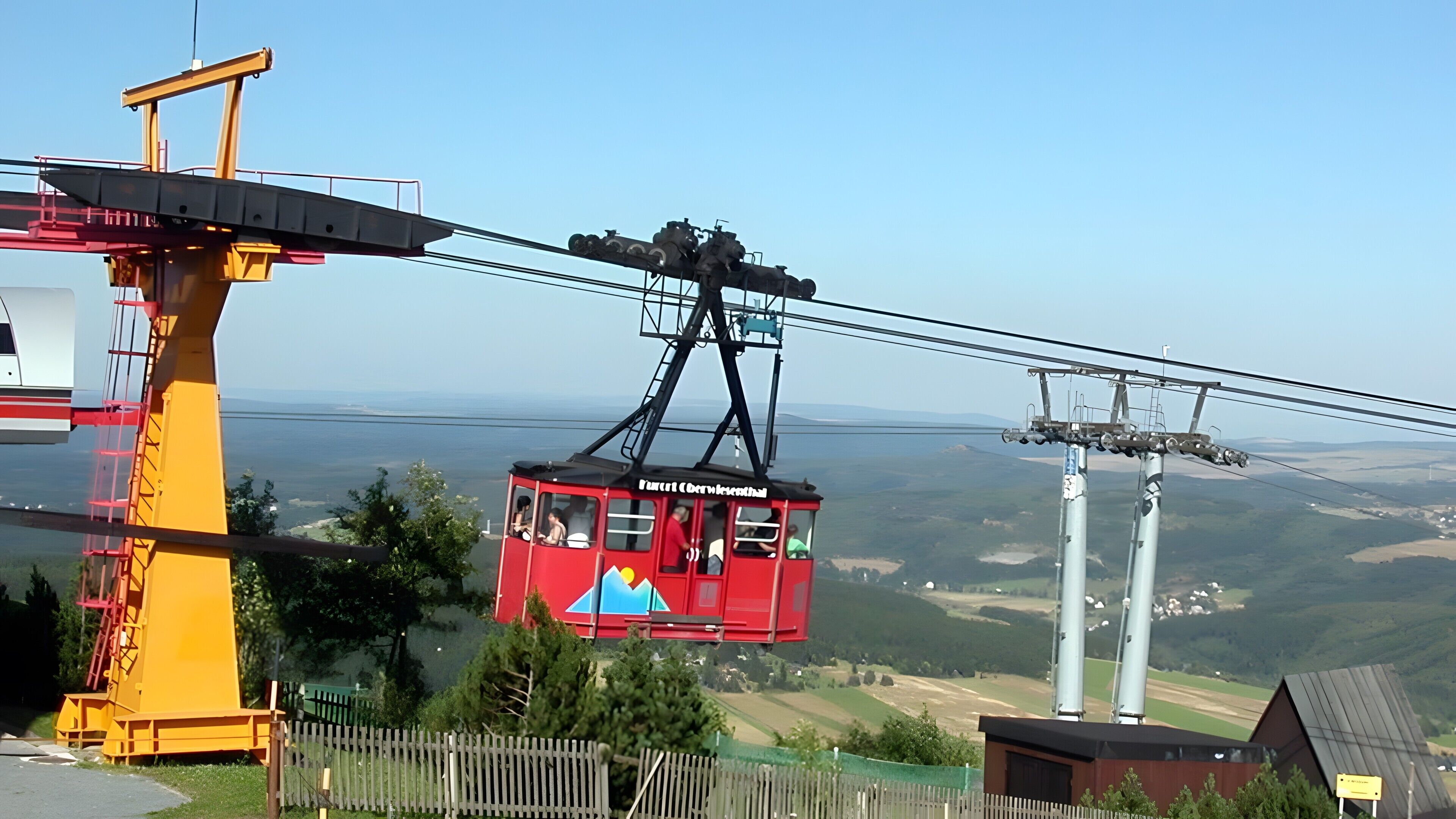Une télécabine rouge, suspendue à des câbles, offrant une vue dégagée sur le paysage environnant.
