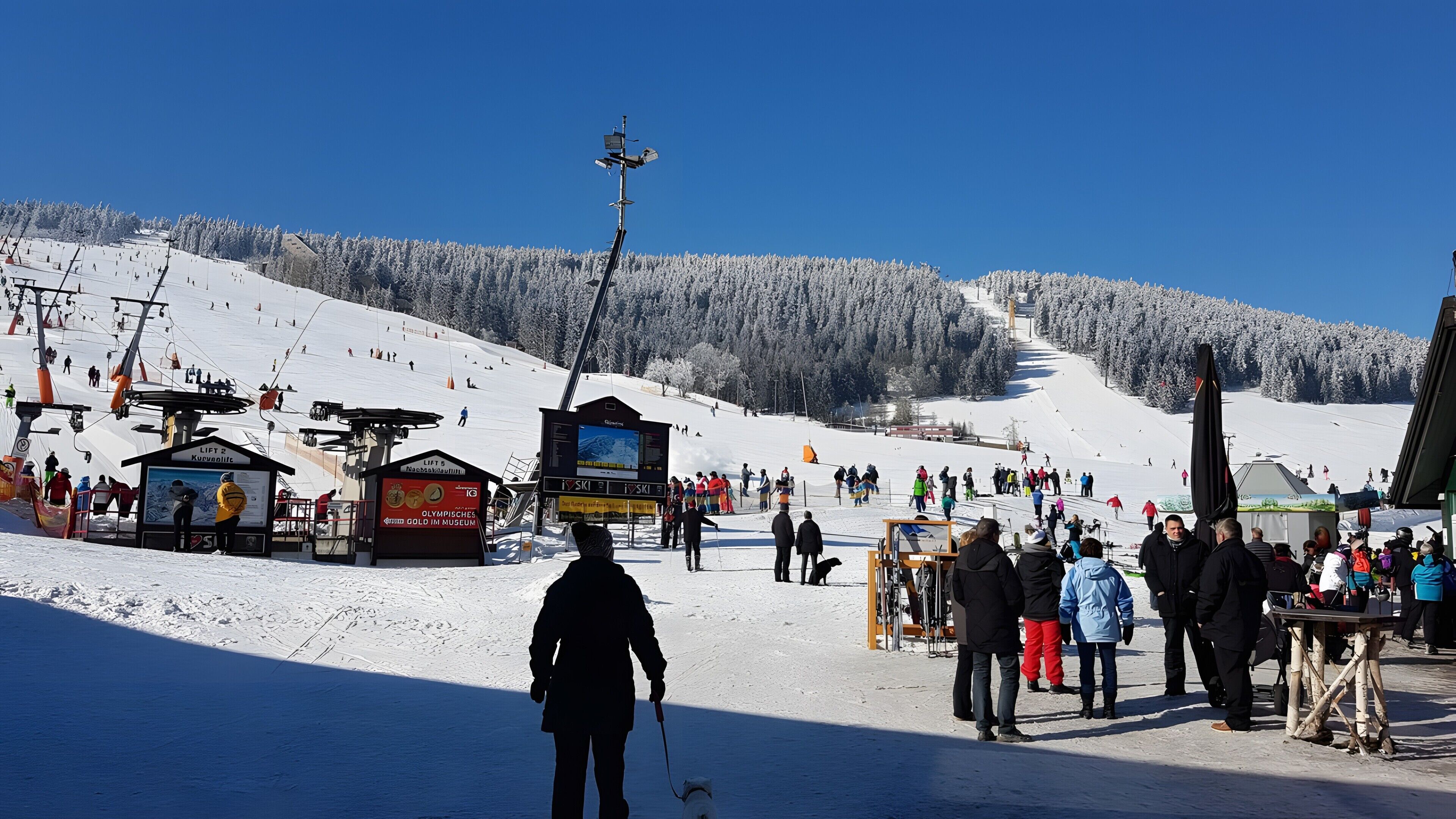 A ski resort with lift stations, ski lifts, and a snowy mountain backdrop.