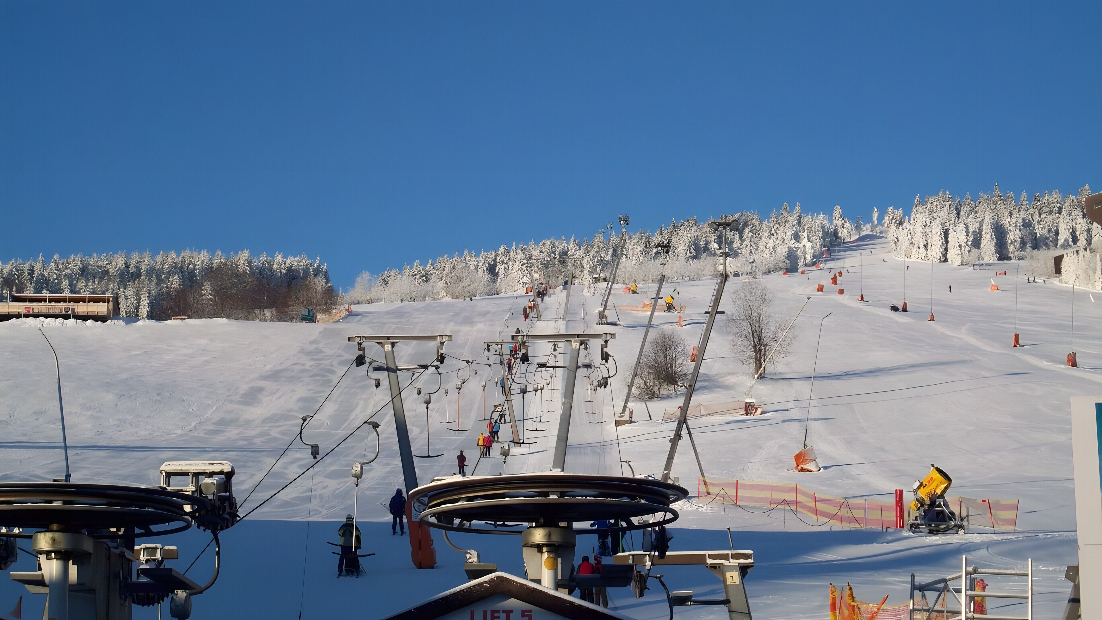 A ski lift with skiers and a snowy landscape.