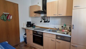 A compact kitchen with a built-in oven, a coffee maker, and a sink. - Holiday Apartment for 5 Guests (61 m²) in Oberwiesenthal (Oberwiesenthal)