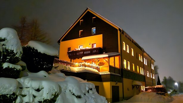 A multi-story building with a balcony, snow-covered surroundings, and warm interior lighting. - Holiday Apartment for 5 Guests (61 m²) in Oberwiesenthal (Oberwiesenthal)