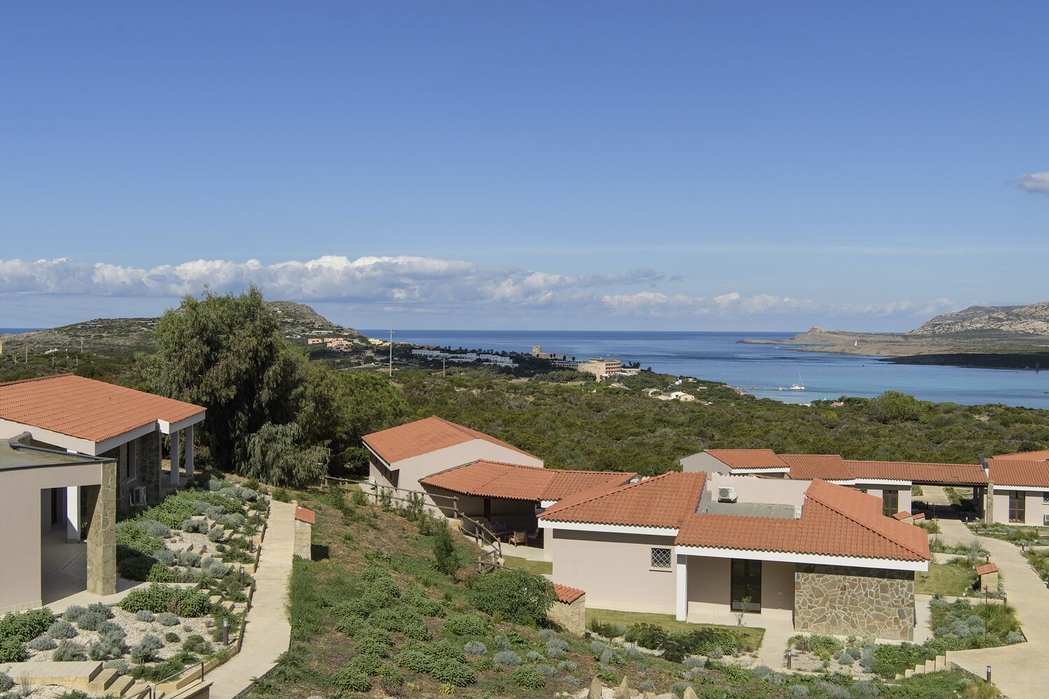 A coastal residential area with terraced houses, a clear view of the sea, and a hilly landscape.