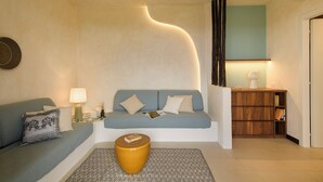 A living room with a sofa, a coffee table, a lamp, and a bookshelf. - Hotel Baia Tartuga (Stintino)