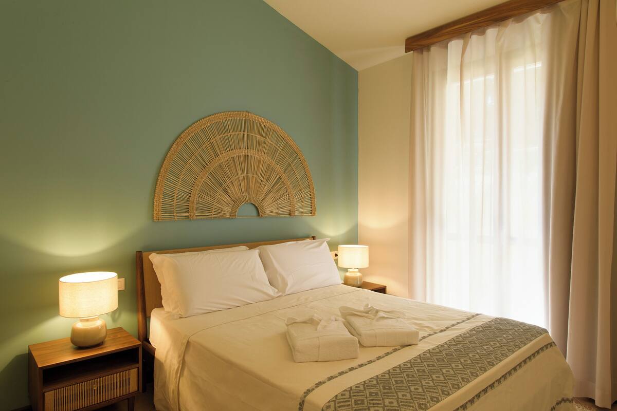 Un lit bien fait, avec des oreillers et une couverture, une lampe de chevet et un élément décoratif fixé au mur.