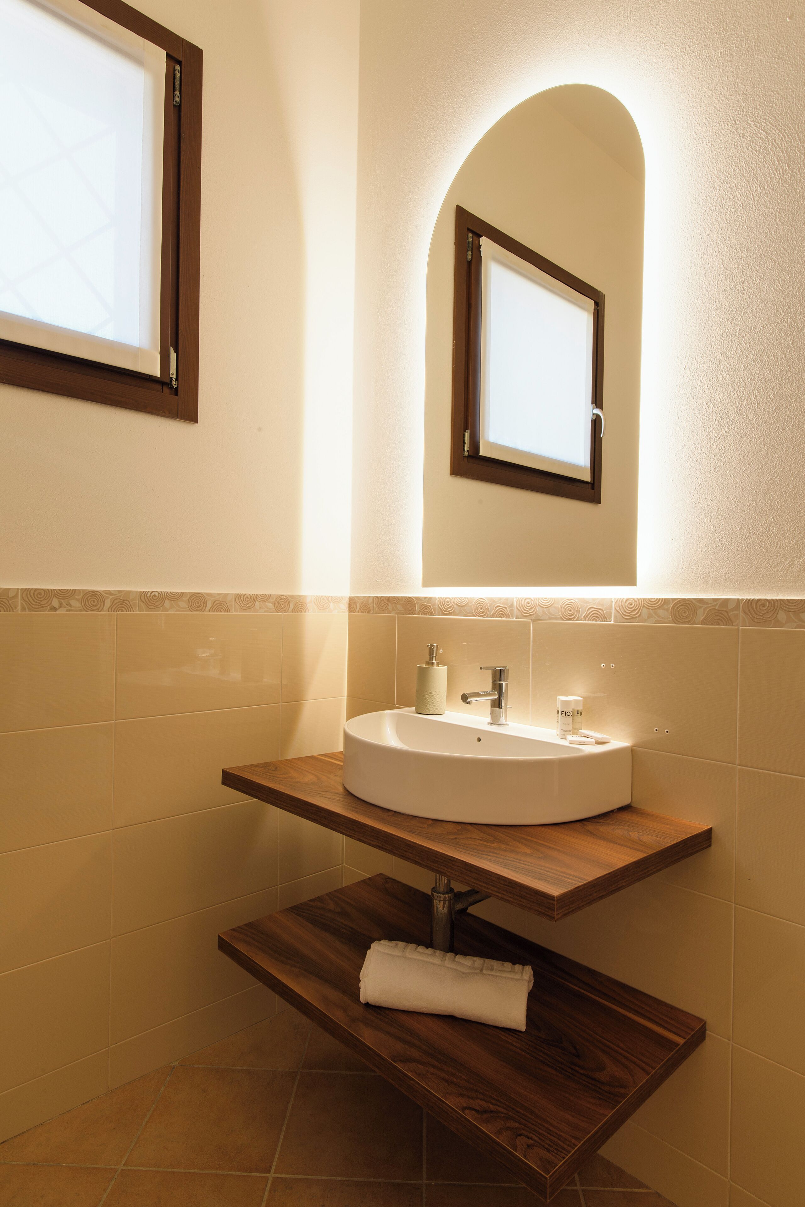 Un baño con tocador de madera, un lavabo, un espejo y un perchero para toallas.