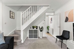 A modern interior with a staircase, a sofa, a chair, and a potted plant. - The Derby Nest - Sleeps 6 (Derby)