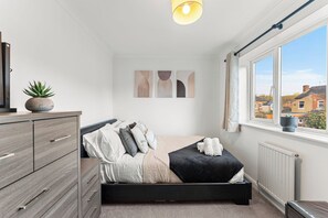 A bedroom with a bed, a dresser, a window with a view, and wall art. - The Derby Nest - Sleeps 6 (Derby)