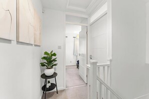 A hallway with a potted plant, a door, and a wall with artwork. - The Derby Nest - Sleeps 6 (Derby)