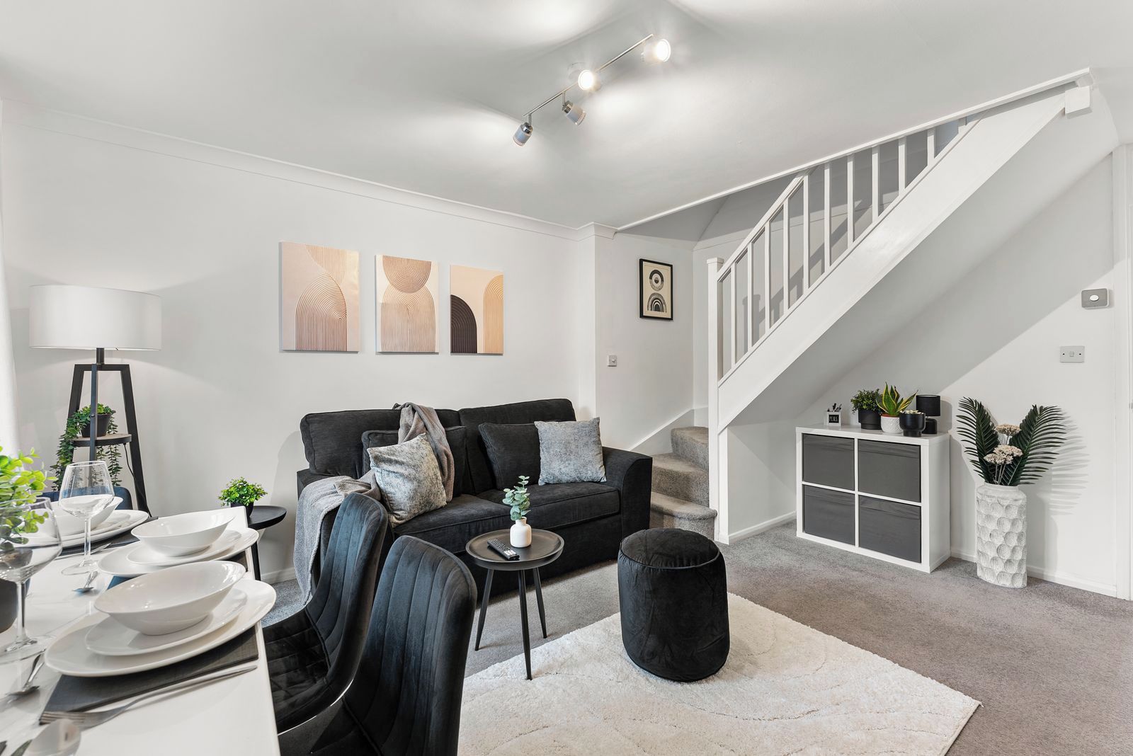 Un salon moderne avec un canapé, une table basse et un escalier menant à un niveau supérieur.