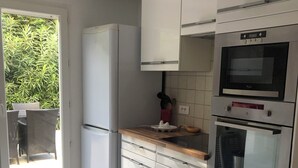 Een keuken met een koelkast, oven en kastjes.