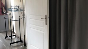 Een kamer met een witte deur, een kapstok, een spiegel en een gordijn.