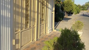 A building with a gated entrance, a signboard, and a paved pathway leading to the entrance.
