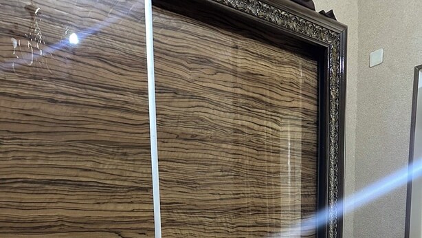 A wooden cabinet with a glass front and decorative metal handles.
