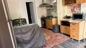 A compact kitchen with a microwave, stove, and wooden cabinets.