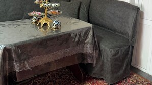 A corner room with a grey sofa, a small table with a decorative item, and a patterned rug.