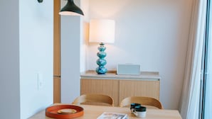 Un espace repas moderne avec une table en bois, deux chaises, une lampe, un vase et un ordinateur portable posé sur un meuble.